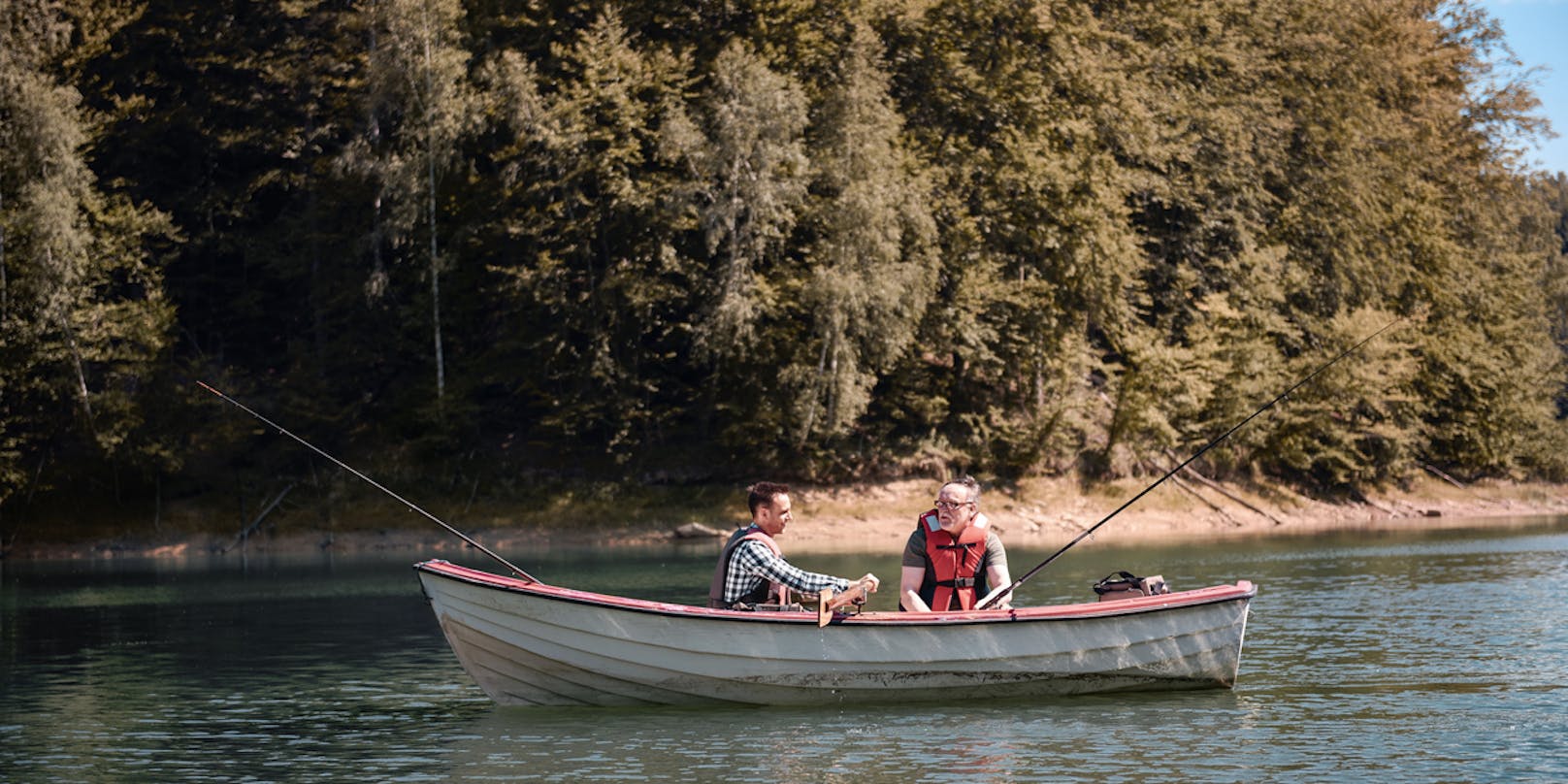 Männer, die in einem ruhigen See vom Boot angeln (Symbolbild)