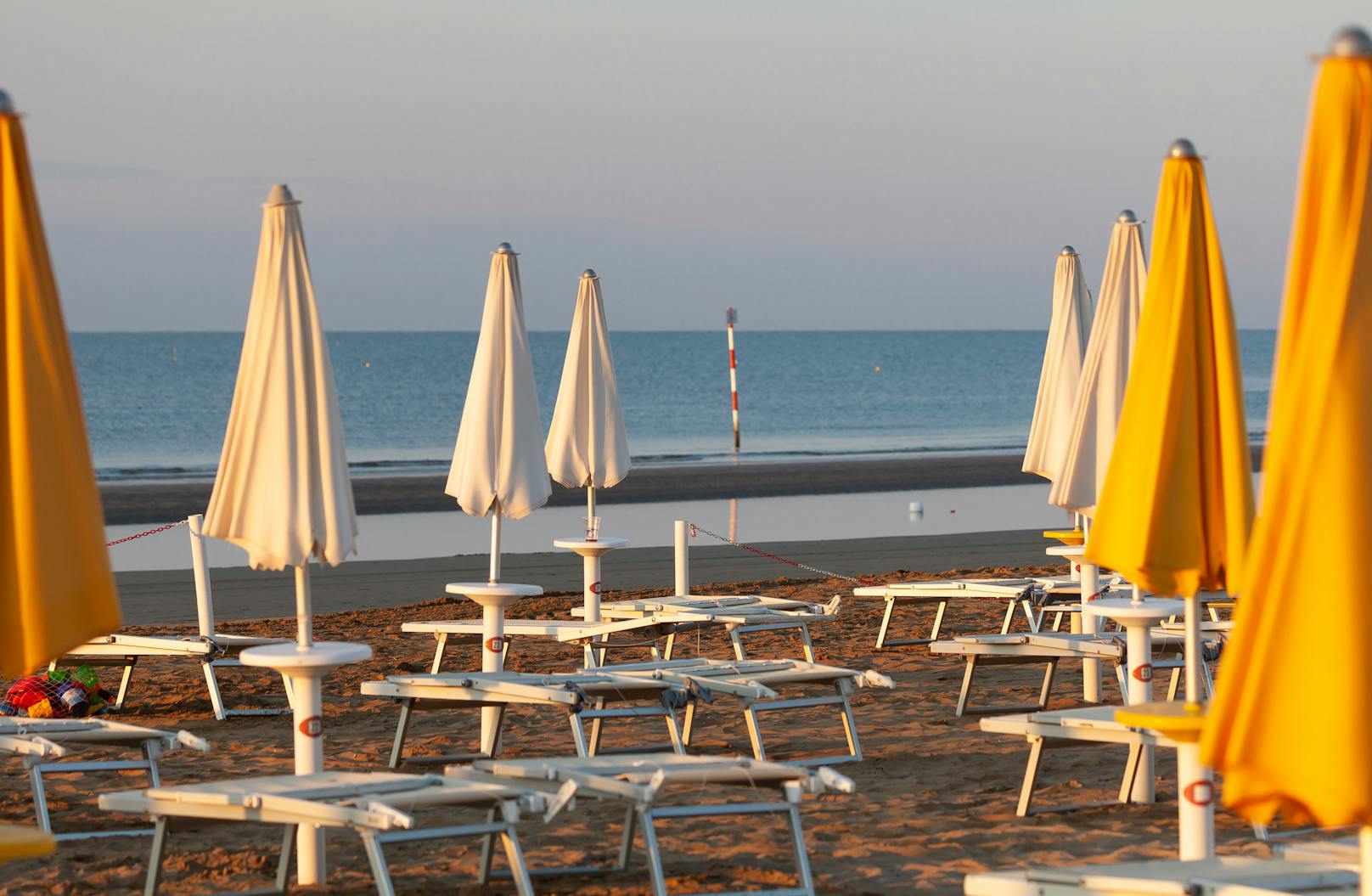 Leere Liegen und zugeklappte Schirme am Strand von Lignano. Archivbild