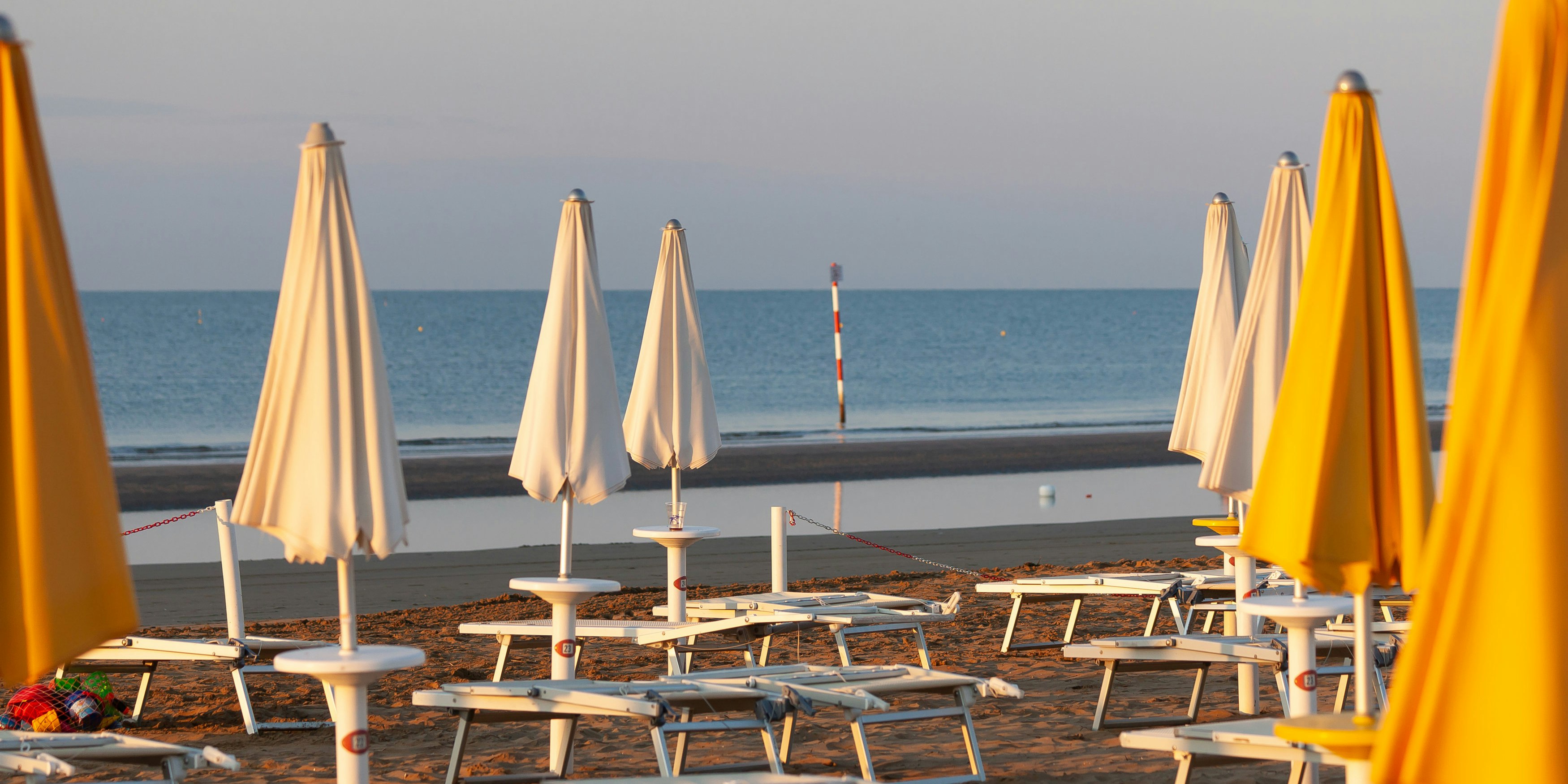 Leere Liegen und zugeklappte Schirme am Strand von Lignano. Archivbild