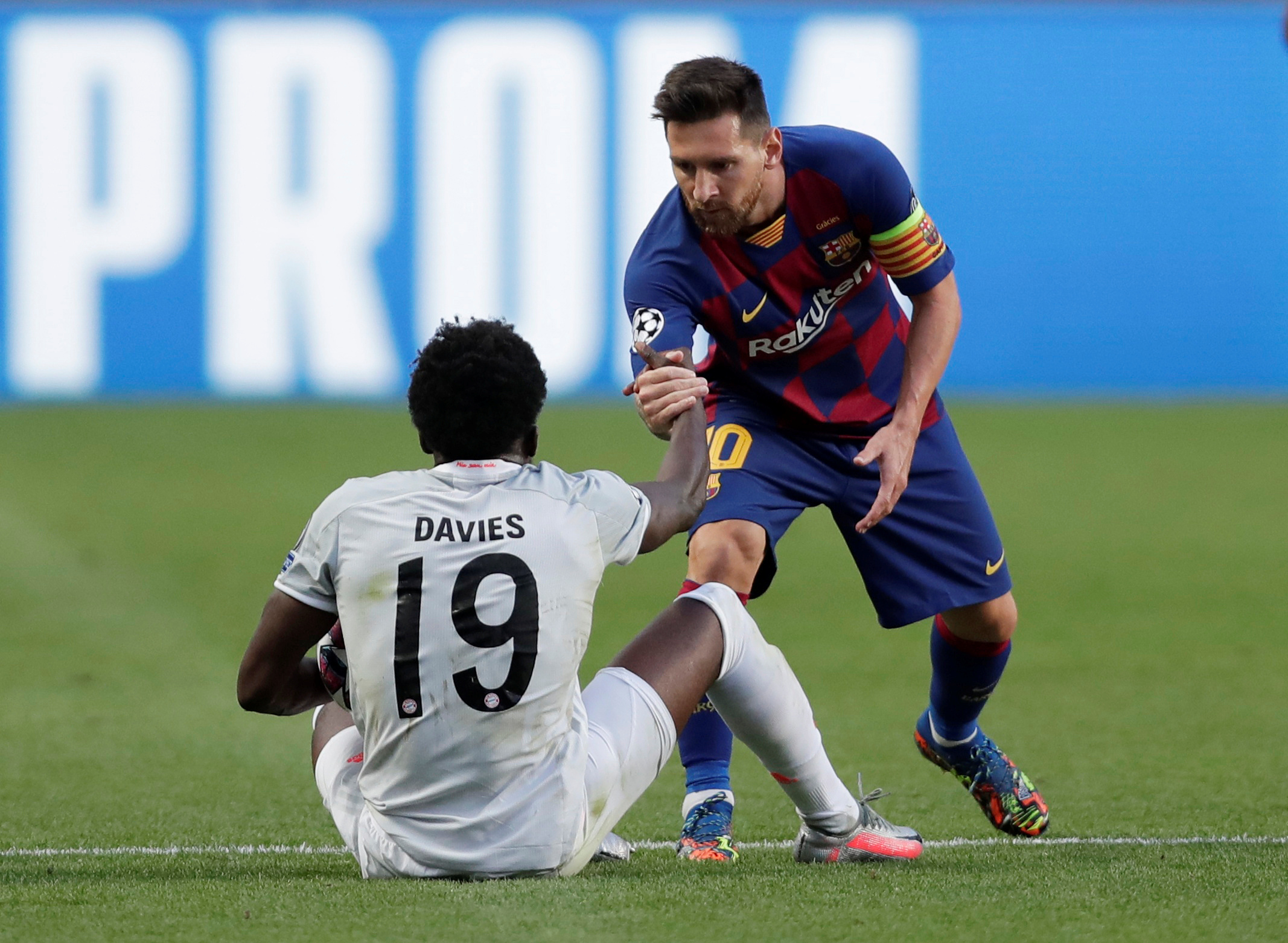 Superstar Lionel Messi hilft seinem Gegenspieler Alphonso Davies auf die Beine.