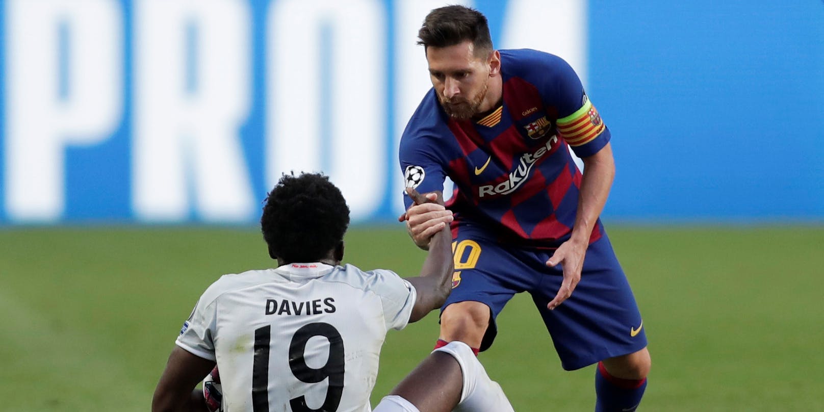 Superstar Lionel Messi hilft seinem Gegenspieler Alphonso Davies auf die Beine.
