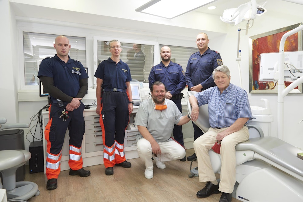 Johann T. (auf dem Behandlungssessel) konnte reanimiert werden. Zu verdanken hat er sein Leben Zahnarzt Waldemar F. (hockend), dem Notfallsanitäter Christopher M., Notärztin Dr. Julia M. sowie den Beamten Thomas E. und Alexander S. (v.l.n.r.)