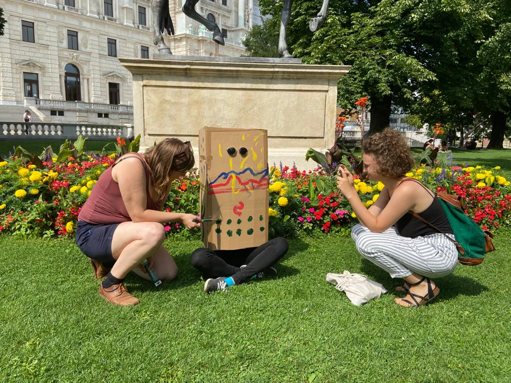 Zwei Damen flankieren die bunte Box.