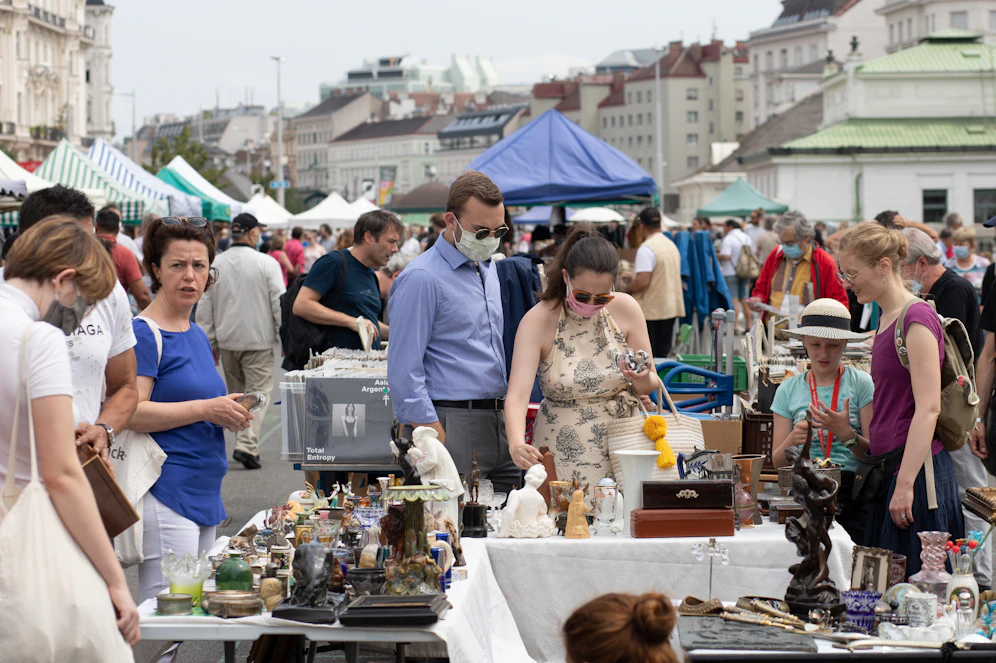 Menschen mit und ohne Mund-Nasen-Schutzmasken stehen zwischen dem Verkaufsständen am Flohmarkt in Wien.