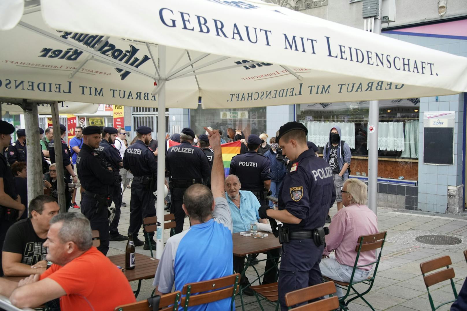 Eine Gruppe mit regenbogenfahnen versuchten, die veranstaltung zu stören. Sie bekamen Polizeischutz - und unflätige Gesten der FPÖ-Fans.