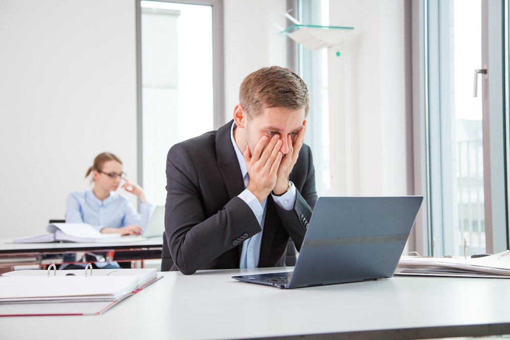 Ein junger Mann schaut erschrocken in seinen Laptop. Symbolfoto