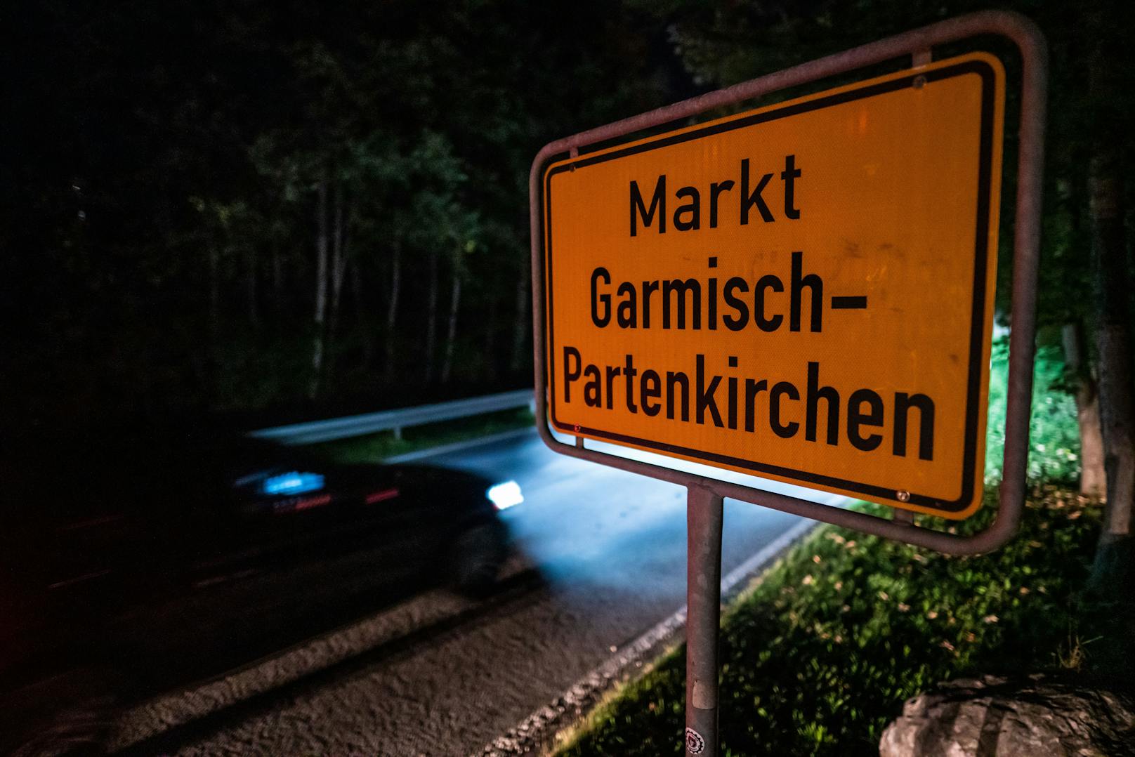 Ein Auto fährt am Ortsschild von Garmisch-Partenkirchen vorbei. Nach einem heftigen Corona-Ausbruch im oberbayerischen Garmisch-Partenkirchen ist noch unklar, mit welchen Konsequenzen die mutmaßliche Verursacherin rechnen muss. Die Behörde geht davon aus, dass der Ausbruch auf eine sogenannte Superspreaderin zurückzuführen ist