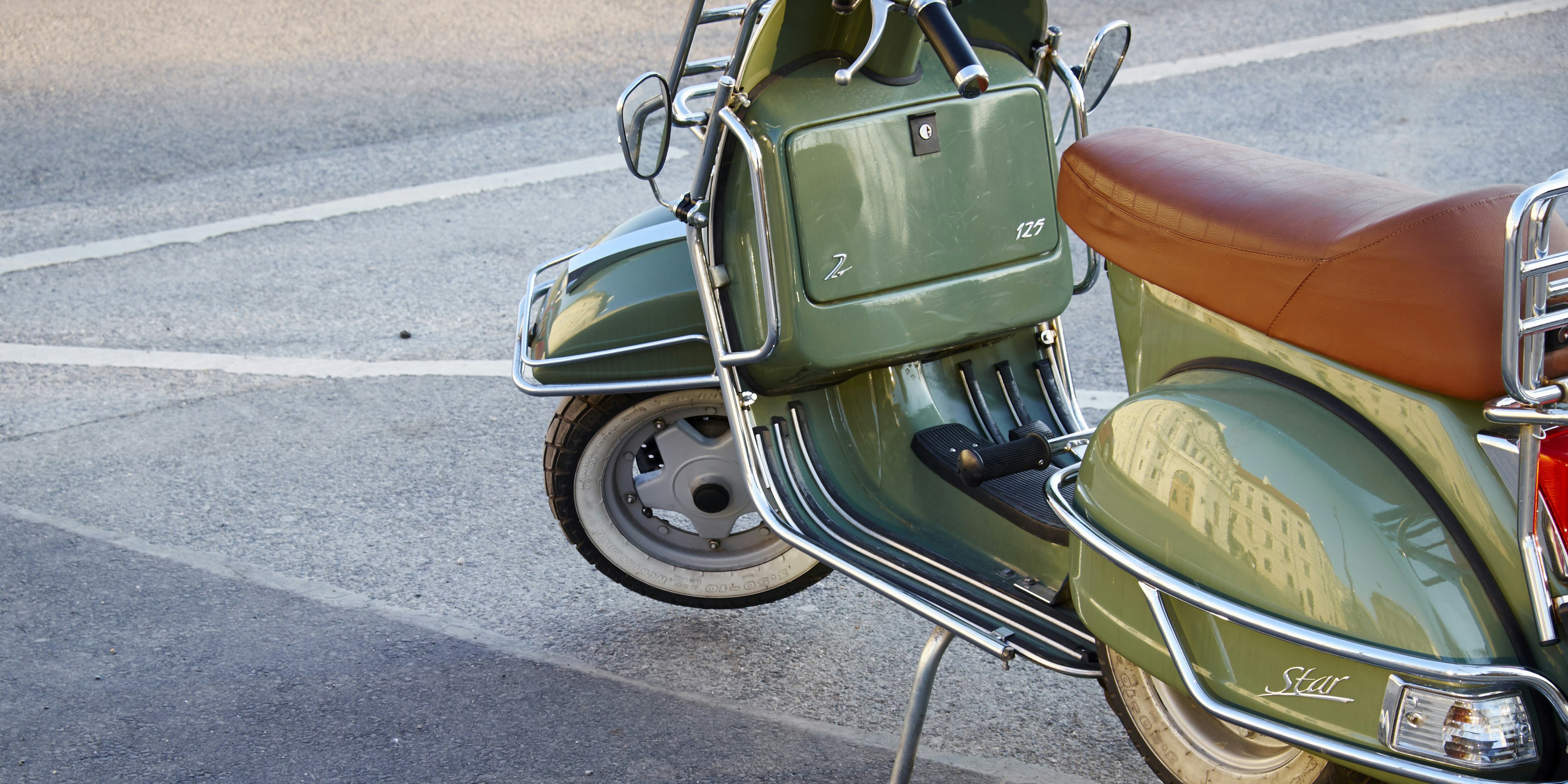 Auf einem Parkplatz abgestellte grüne Vespa Star. Symbolbild
