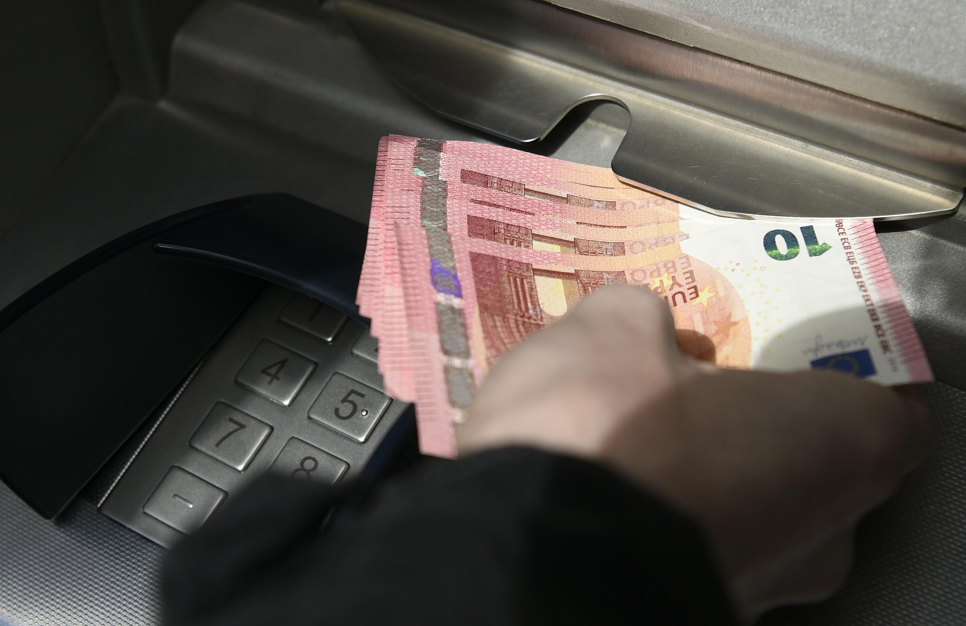 Ein Person beim Abheben von Bargeld bei einem Bankomaten. Symbolfoto
