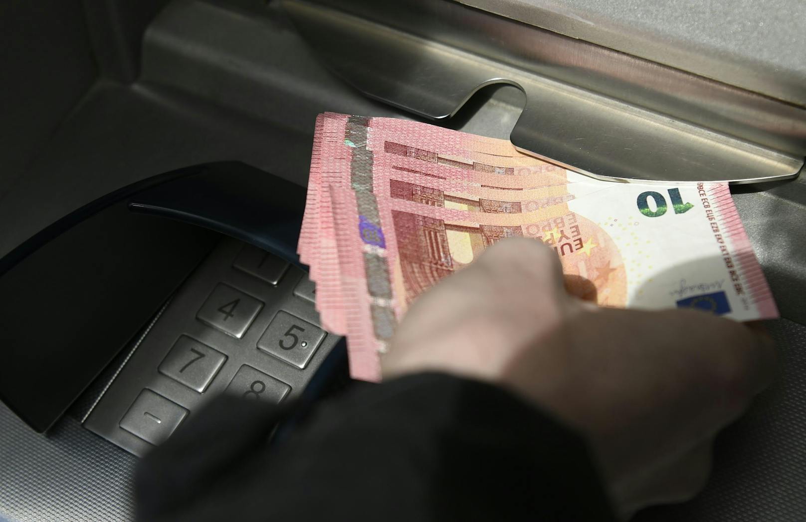 Ein Person beim Abheben von Bargeld bei einem Bankomaten. Symbolfoto