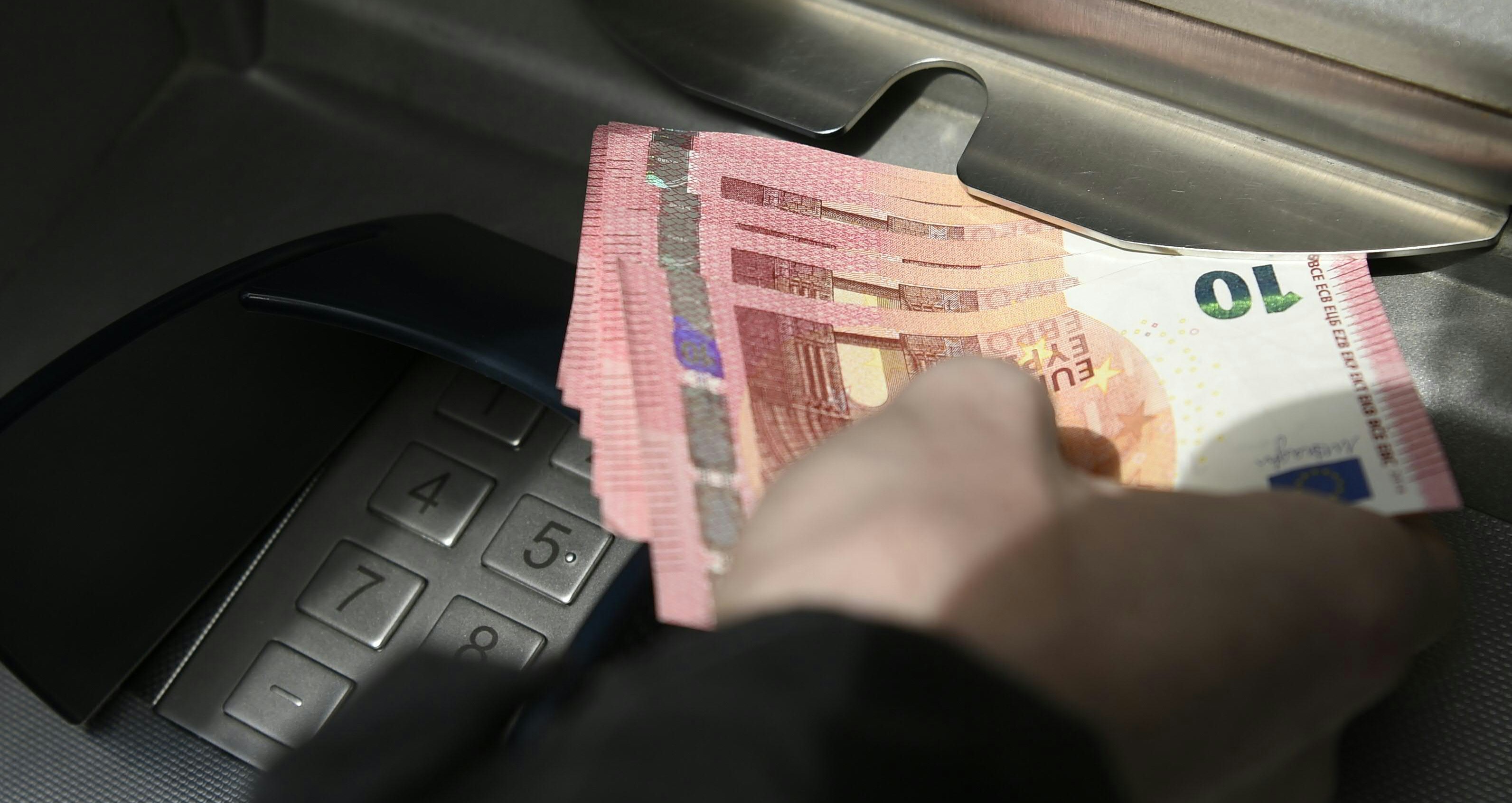 Ein Person beim Abheben von Bargeld bei einem Bankomaten. Symbolfoto