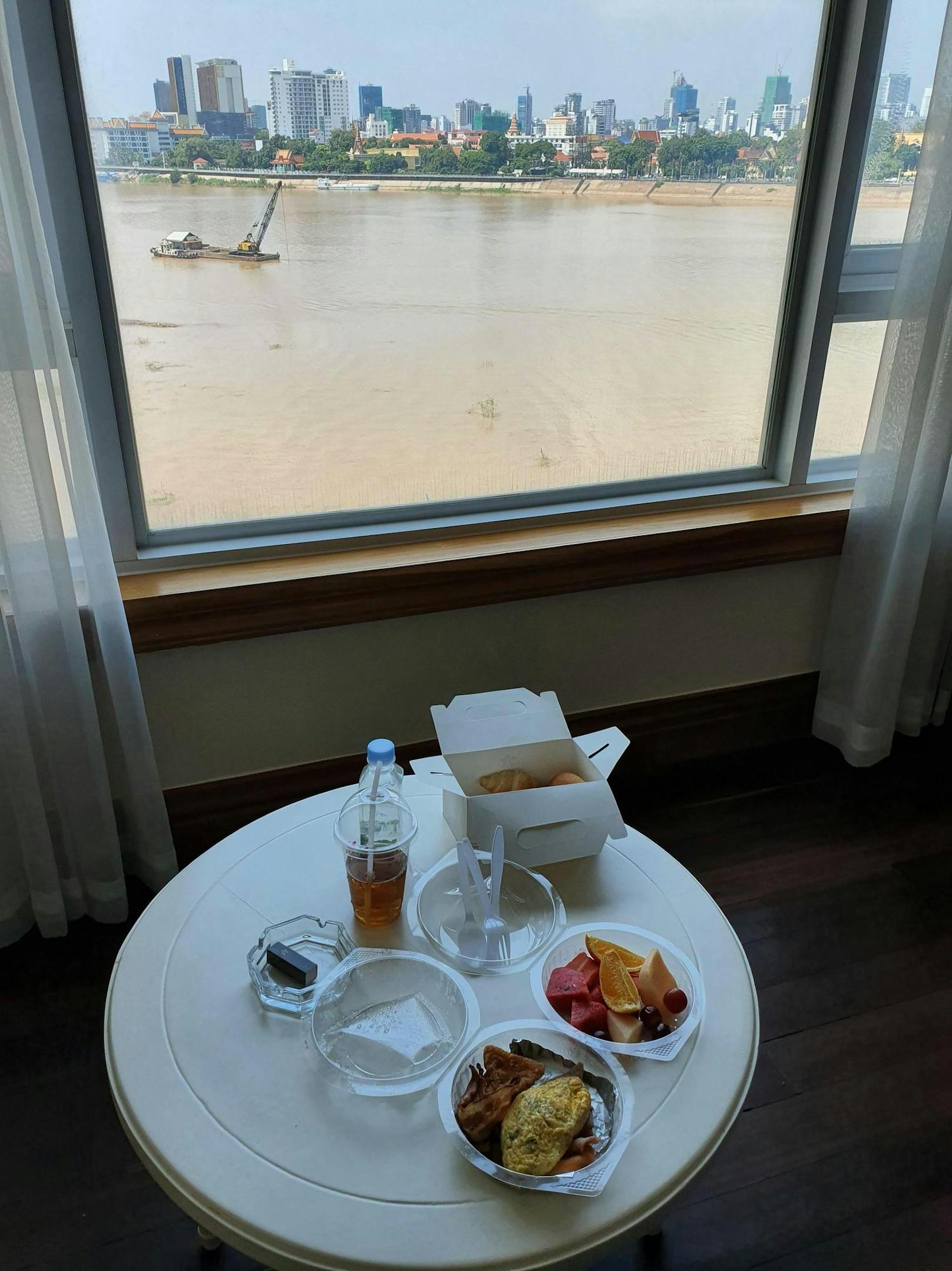 Die Aussicht beim Essen ist nicht schlecht: Er blickt vom Zimmer aus auf den Tonle Sap Fluss und die dahinter aufragende Skyline von Phnom Penh.