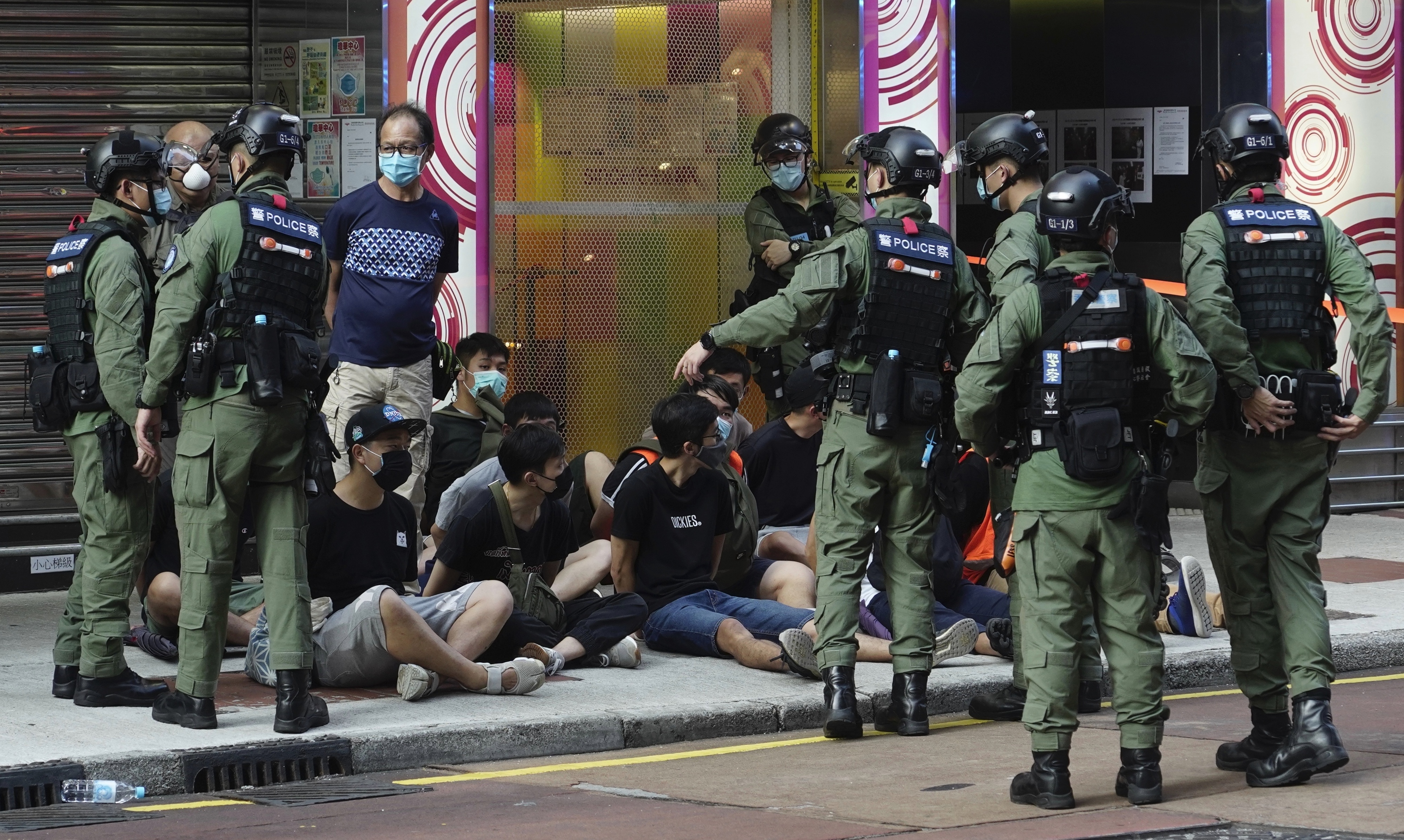 Auf dem Boden sitzende Personen werden von Polizeibeamten auf einer Straße in der Innenstadt von Hongkong verhaftet.