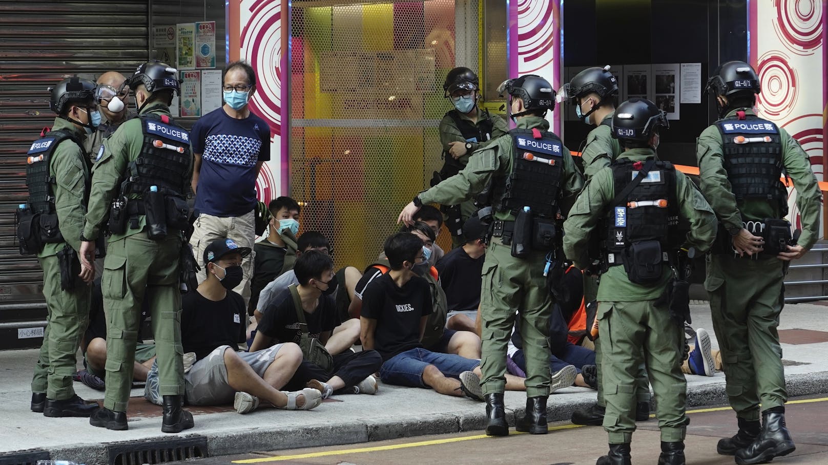 Auf dem Boden sitzende Personen werden von Polizeibeamten auf einer Straße in der Innenstadt von Hongkong verhaftet.