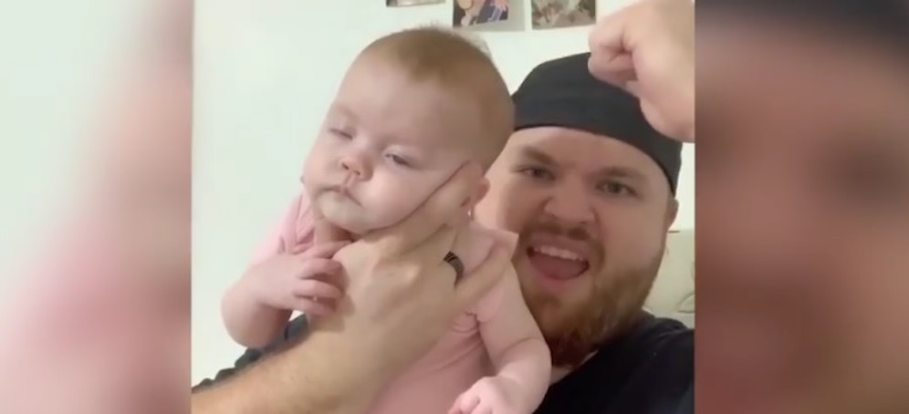 Die Freude des Vaters, nachdem er sein Baby durch Anwendung eines hilfreichen Tipps in Sekunden zum Einschlafen gebracht hat, ist ihm ins Gesicht geschrieben.<br>