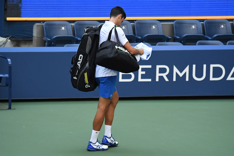 Novak Djokovic schleicht nach der Disqualifikation vom Platz.