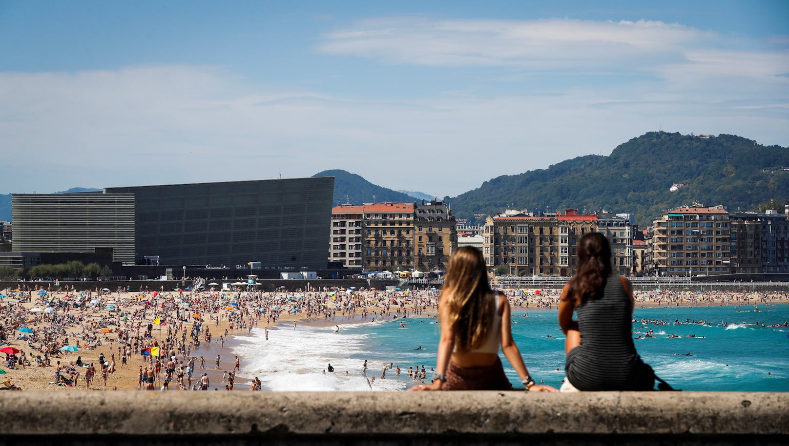 Besucher genießen den strahlenden Sonnenschein am Zurriola-Strand von San Sebastian, 12. August 2020