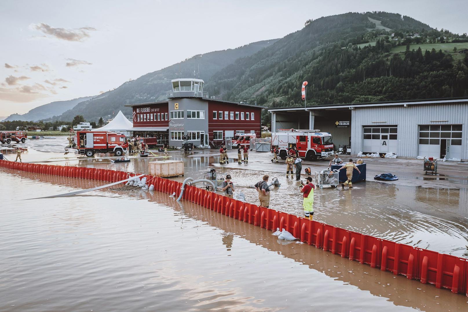 Zell am See: Einsatzkräfte der Feuerwehr pumpen nach den Sintflut-Unwettern Wasser am überfluteten Flugplatz ab