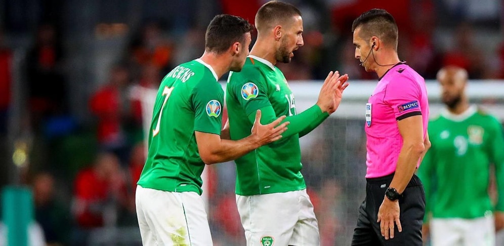 Carlos Del Cerro Grande will Stevens die Gelbe Karte für sein Foul an Mbabu geben, findet den Karton in seinen Taschen aber nicht.