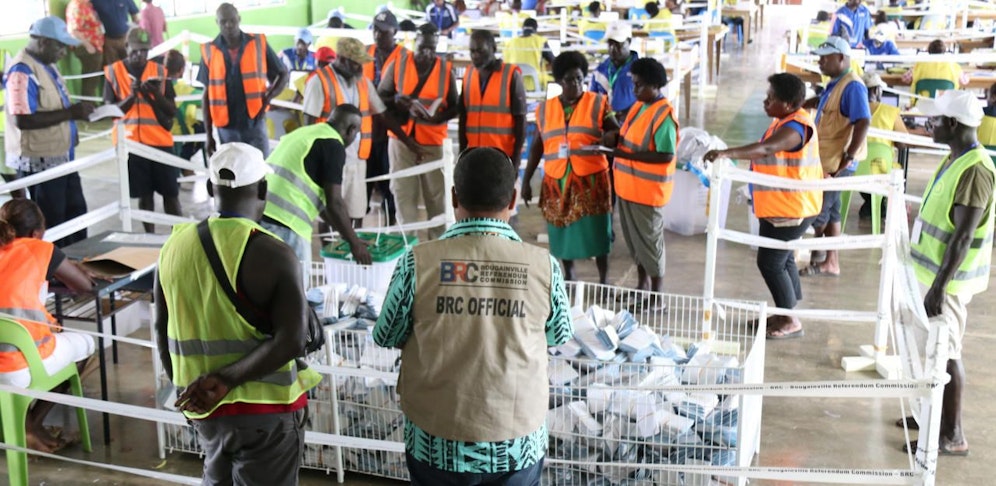 Beamte sammeln die Stimmzettel für die Auszählung ein.
