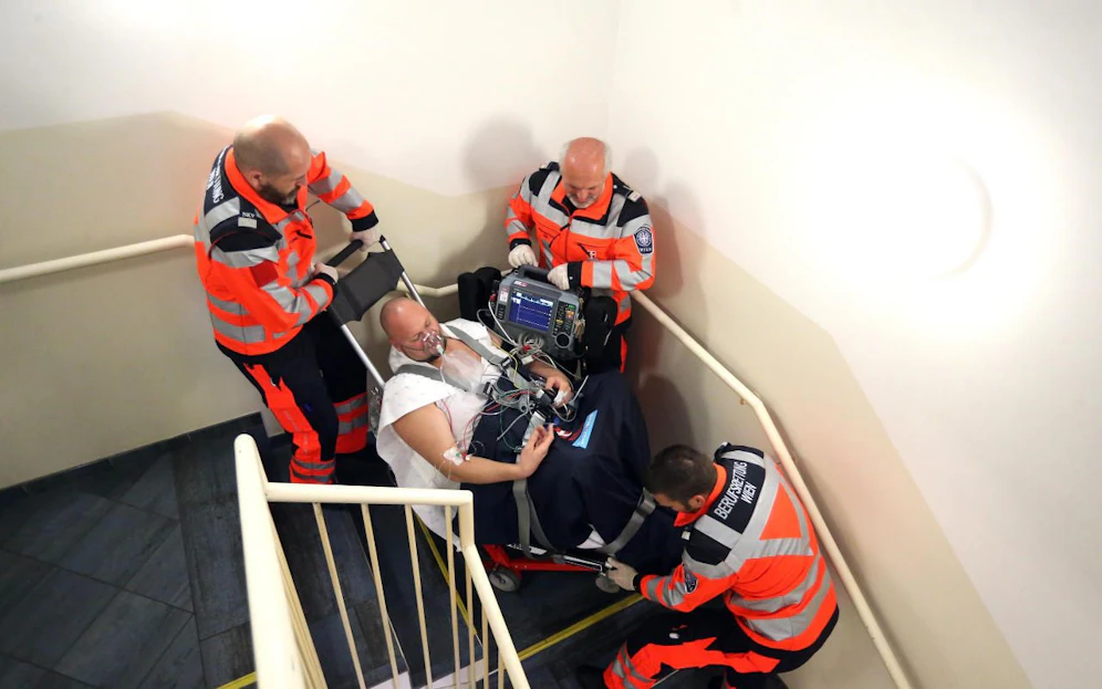 Auf einer speziellen Trage wird der Patient durch Stiegenhaus gebracht.