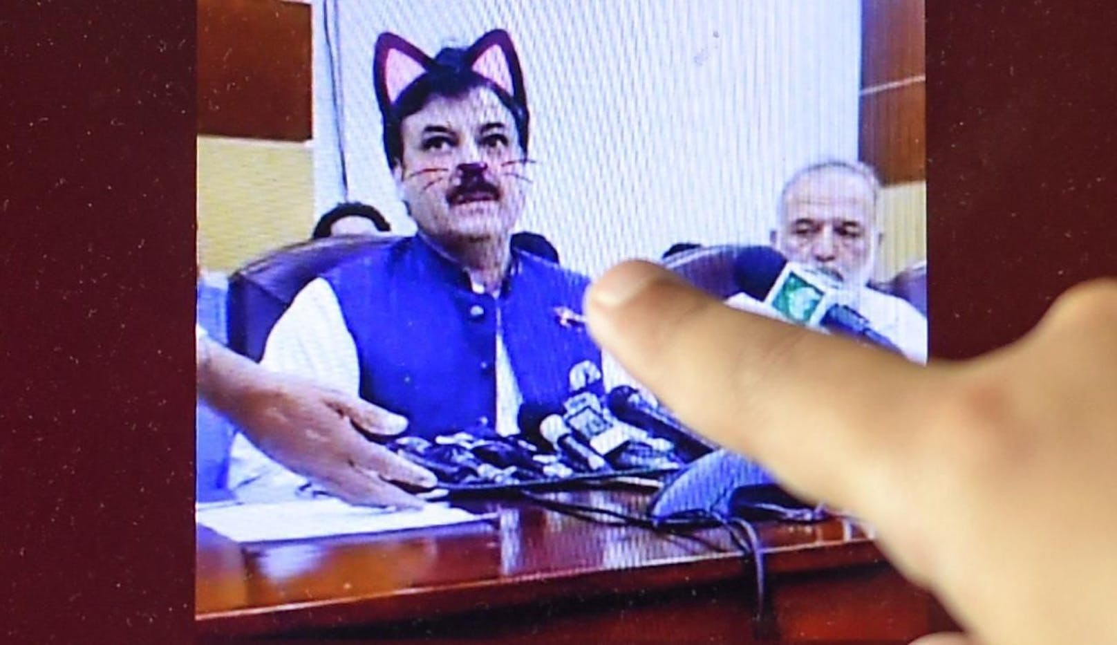 Ein Kind zeigt amüsiert auf die Katzenöhrchen der Politiker.