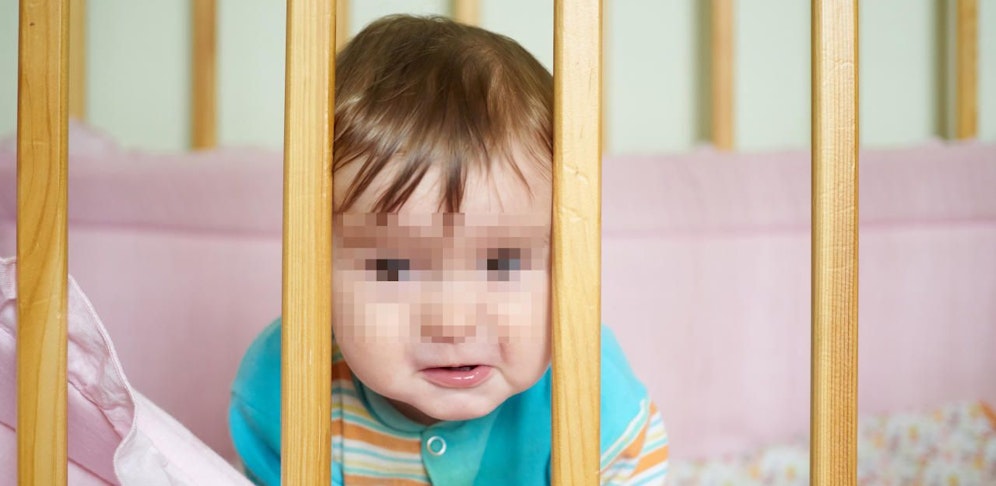 Die Kleine lag im Gitterbett, bekam von der Aufregung der Mutter nichts mit.