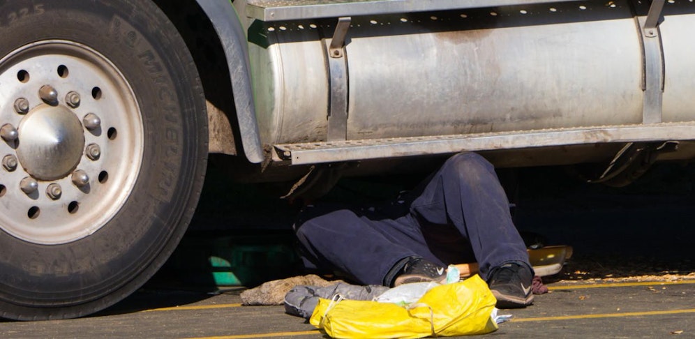 Symbolbild eines Mannes, der an einem Lkw arbeitet.