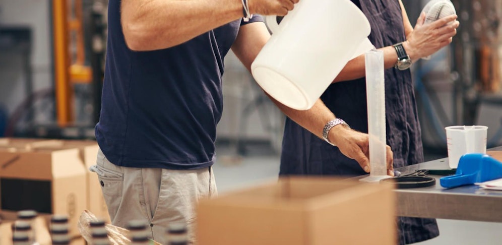 Symbolbild eines Mannes und einer Frau beim Schnaps herstellen.