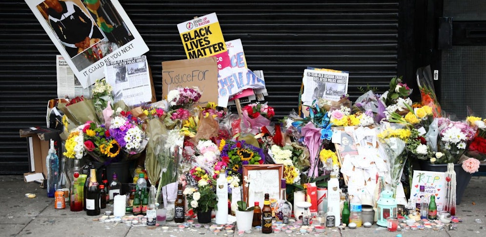 Blumen und Andenken an Rashan Charles vor einem Shop in London.
