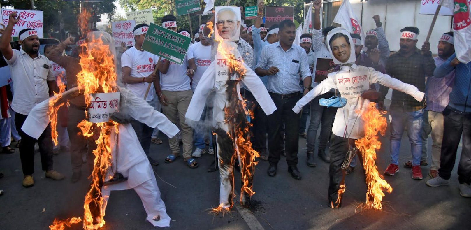 Aktivisten der All Assam Studentenverbindung verbrennen aus Protest Figuren, de Innenminister Amit Shah, die Premierminister Narendra Modi und den Ministerpräsidenten von Assam Sarbananda Sonowal zeigen.