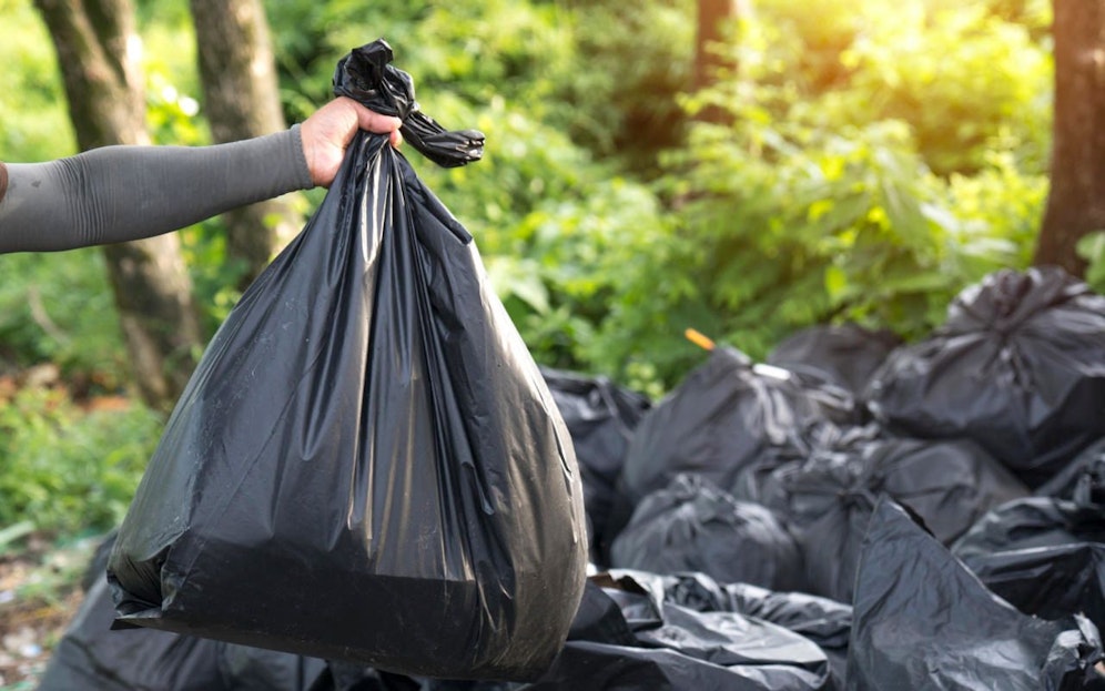Ein Mann bringt Müllsäcke nach draußen. Symbolfoto