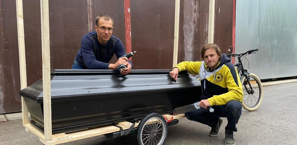 Dominik Schilcher und Erik Schnaitl (stehend) mit dem Holzsarg
