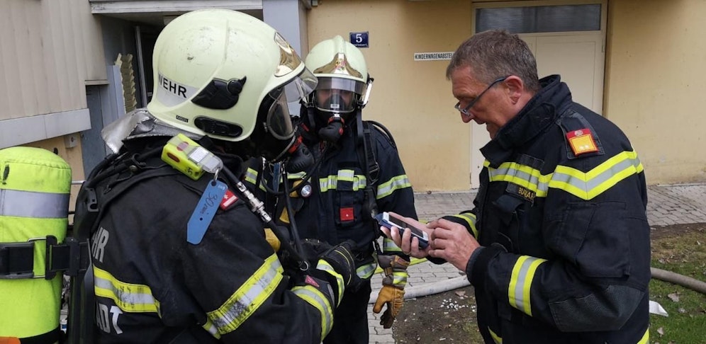 Besprechung vor der Wohnhausanlage. Die Atemschutztrupps der Feuerwehr stehen im Einsatz.