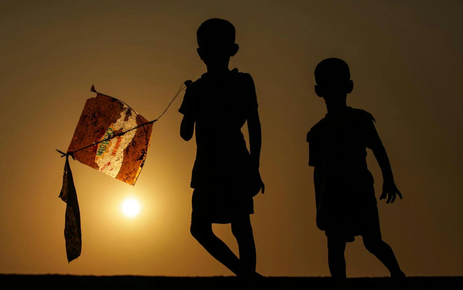 Indische Kinder spielen mit einem Flugdrachen.