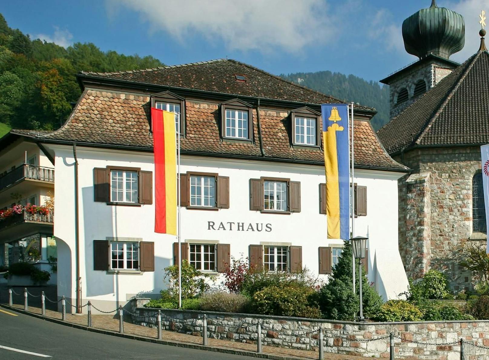 Das Rathaus von Triesenberg im Fürstentum Liechtenstein. Mit der Flagge des Fürstenhauses und der Flagge von Triesenberg.