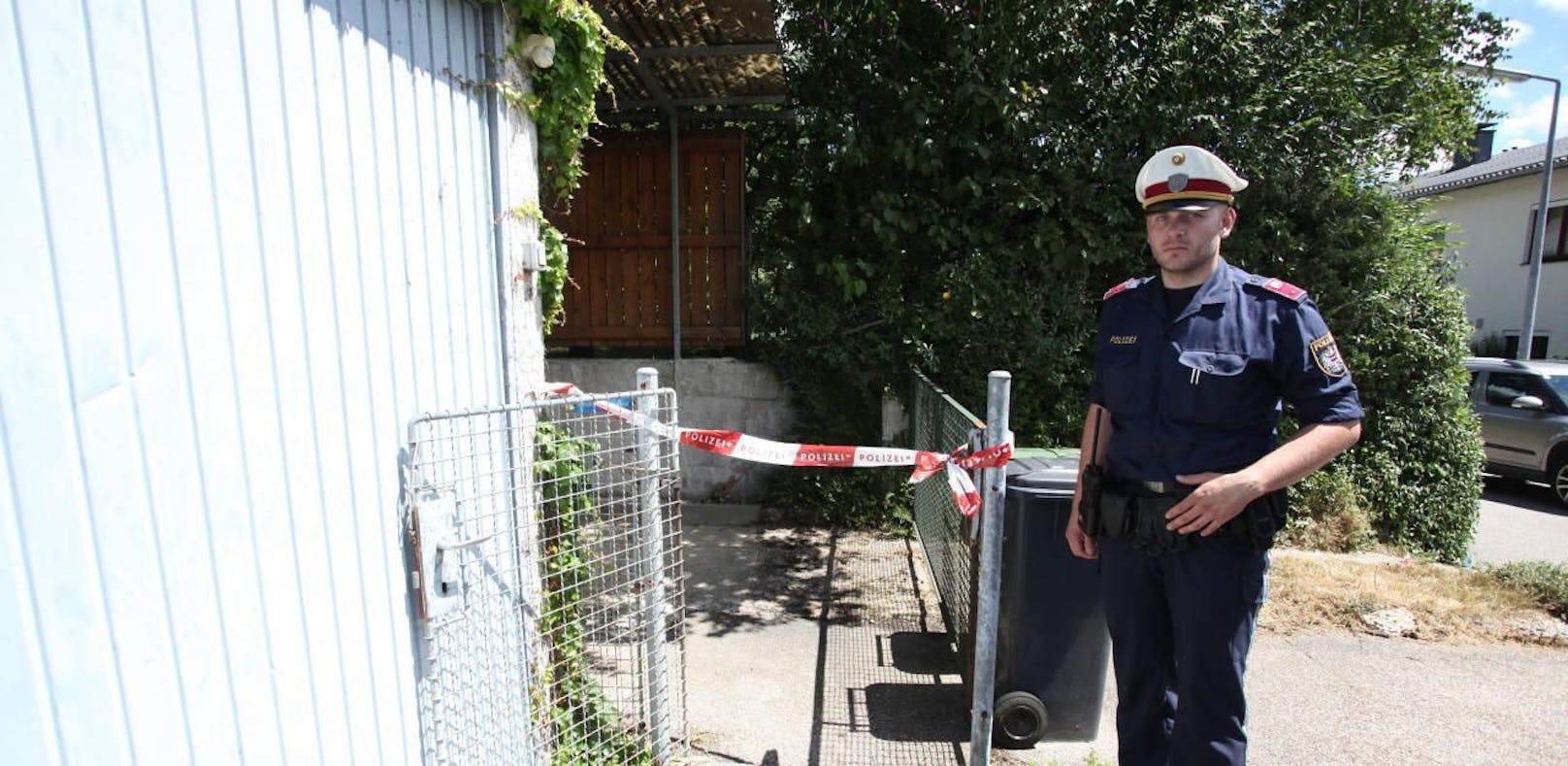 Ein Polizeibeamter bewacht den Eingang des Hauses in Linz-Dornach, wo der Doppelmord passierte.