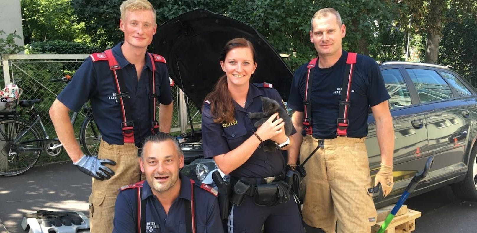 Eine Polizistin mit dem geretteten Kätzchen und den Helfern der Feuerwehr.