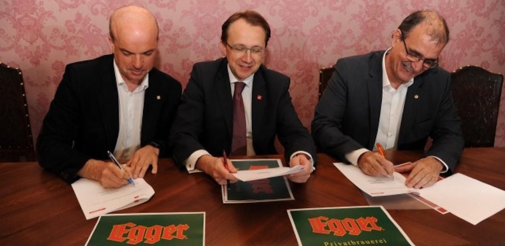 Egger-Geschäftsführer Bernhard Prosser (li.) und Kurt Ziegleder unterzeichnen mit Bürgermeister Matthias Stadler die Kooperation.