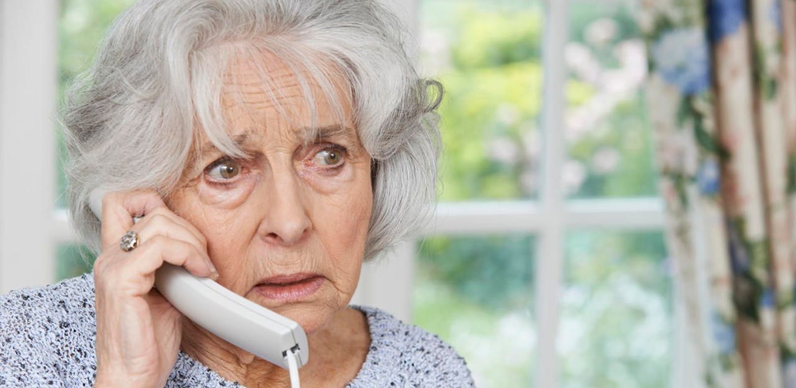 Symbolfoto einer besorgten Frau am Telefon. 