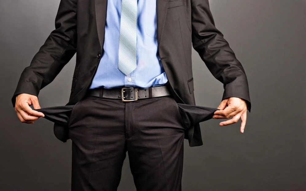 Business man showing his empty pockets  on gray background