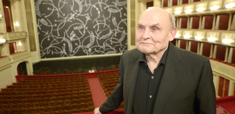 Der Künstler Oswald Oberhuber vor dem Hintergrund des vom im gestalteten Eisernen Vorhanges in der Wiener Staatsoper.