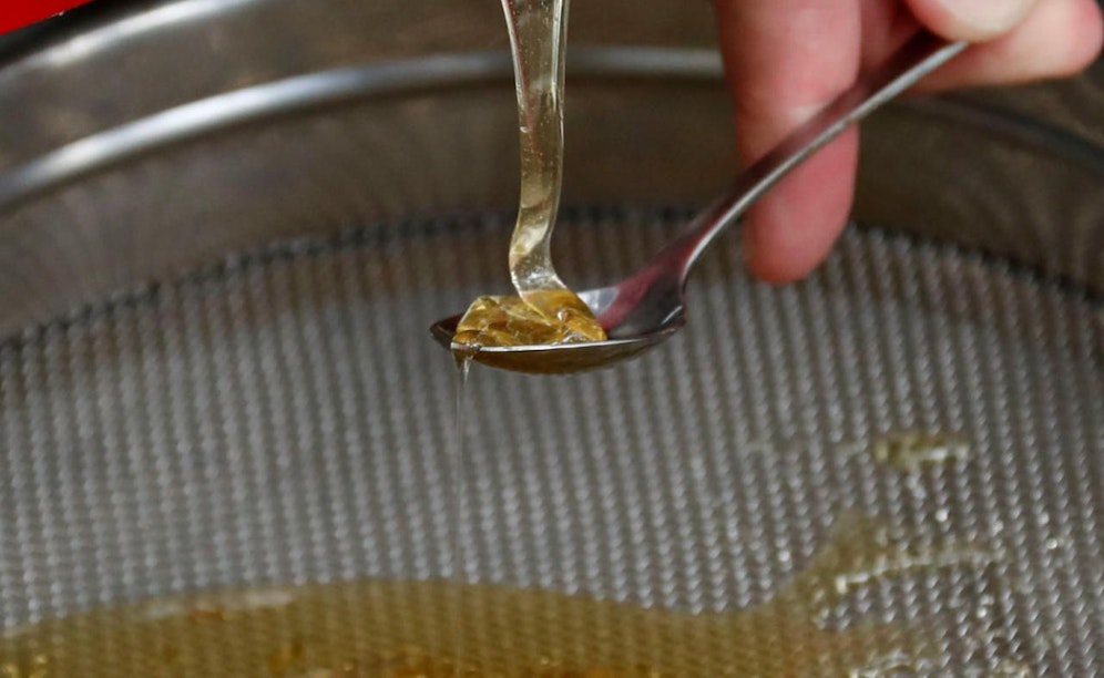A journalist prepares to taste the harvest of honey from tens of thousands honeybees permanently placed in a courtyard of an office building at the lower house of the German parliament Bundestag in Berlin, Germany, August 23, 2017. REUTERS/Fabrizio Bensch - RC1A2FFBC600