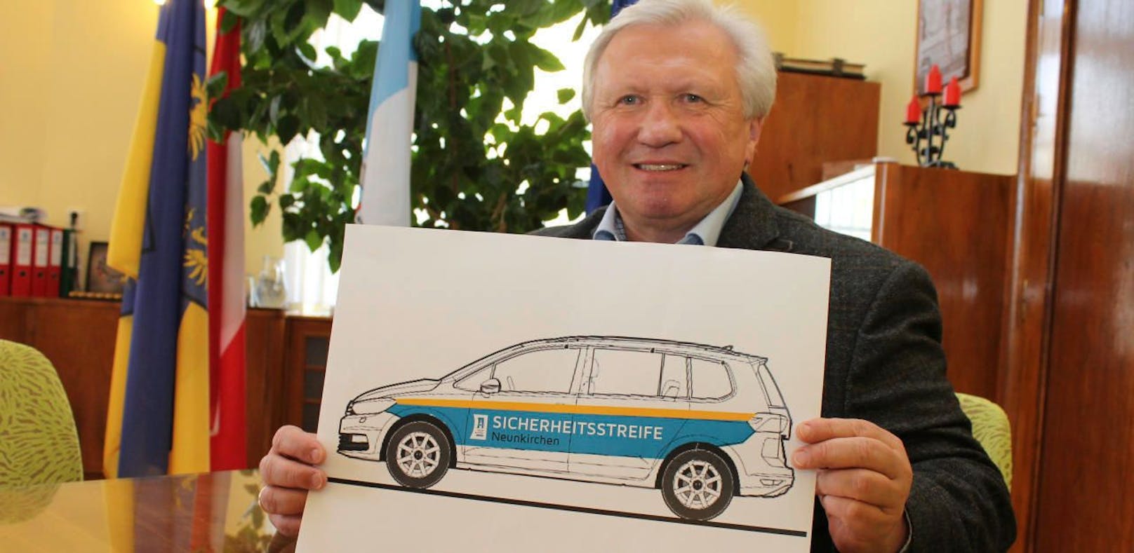 Auf einem Taferl präsentiert Bürgermeister Herbert Osterbauer das Design der Sicherheitsstreife. 