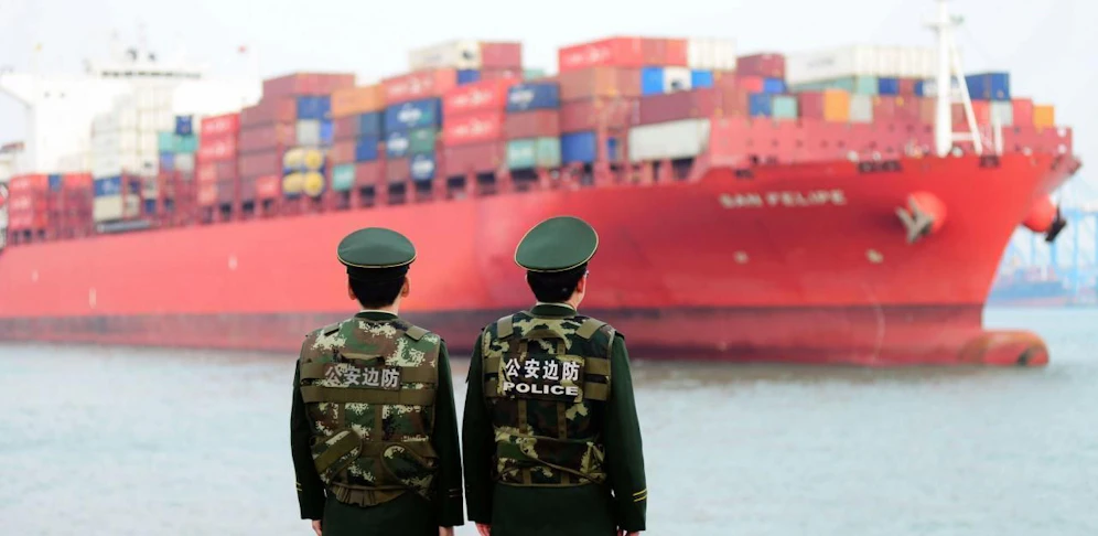 Chinesische Polizisten haben ein waches Auge auf ein Frachtschiff im Hafen von Qingdao.