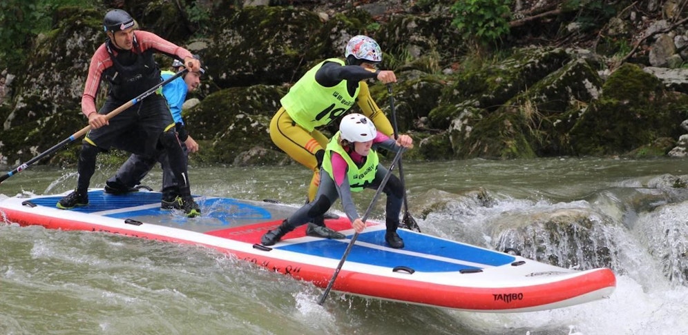 Vier Personen auf einem einzigen Mega-Standup-Paddleboard. 