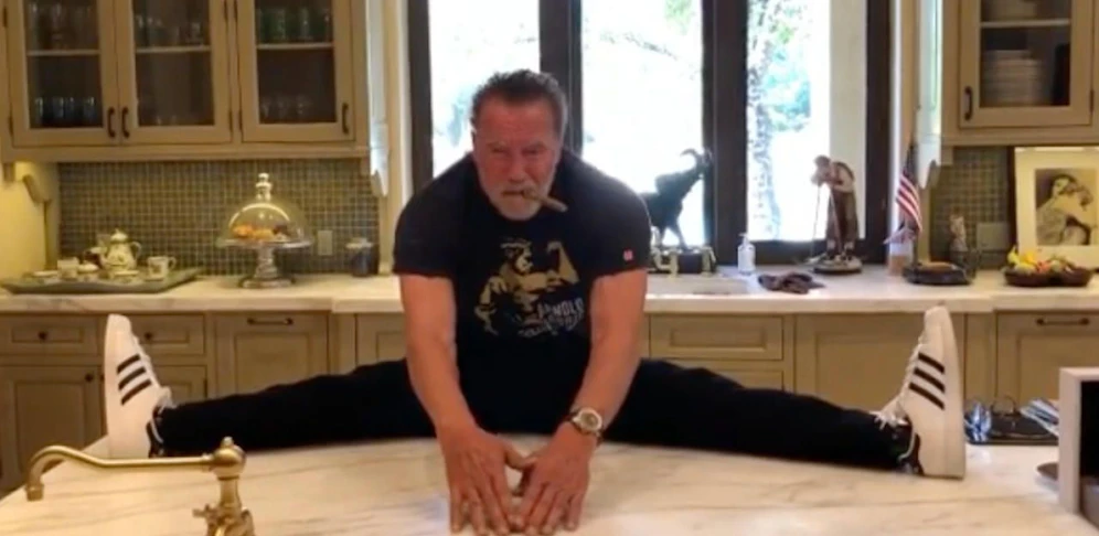 Arnold Schwarzenegger beim lässigen Spagath am Küchentisch