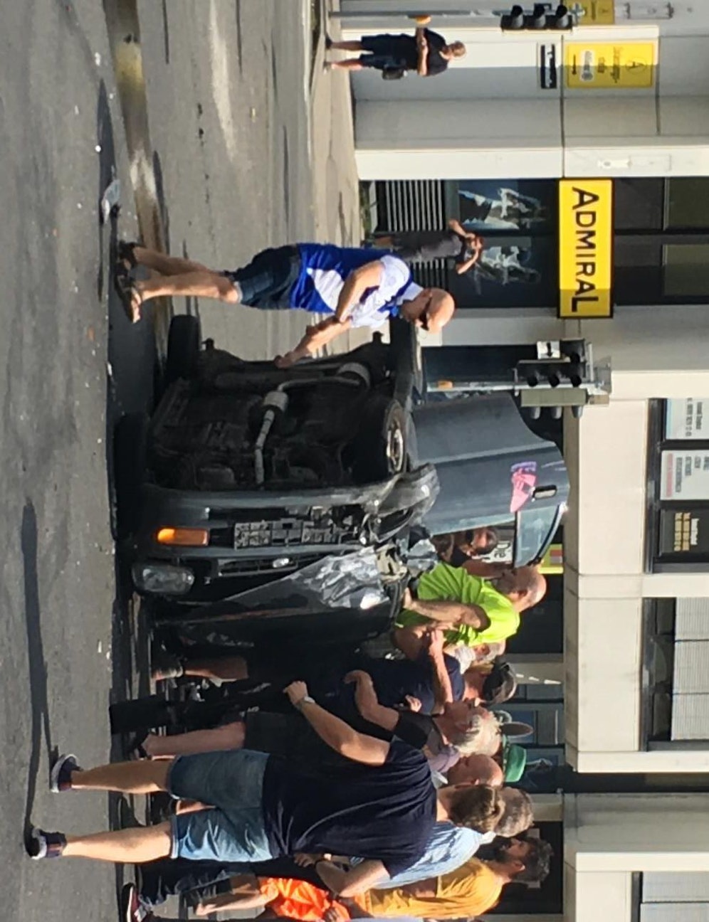 Passanten helfen dem Unfalllenker aus dem umgestürzten Auto.