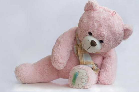 Rosa Teddybär mit farbigen Pfoten und Gesicht. Symbolfoto