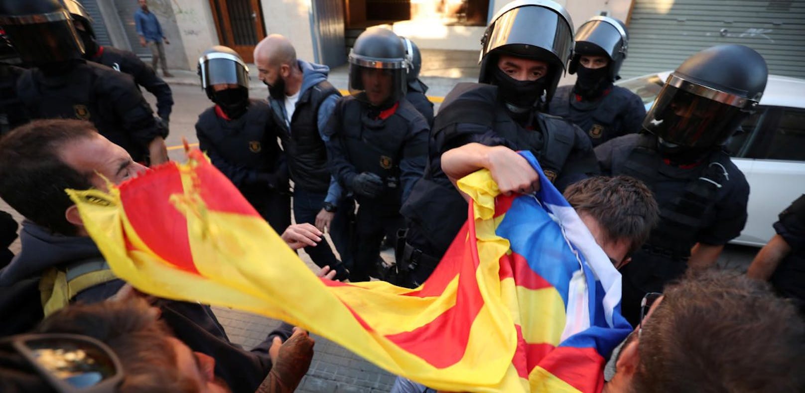 Polizisten rangeln mit Demonstranten in Barcelona, bevor Hausdurchsuchungen durchgeführt werden.